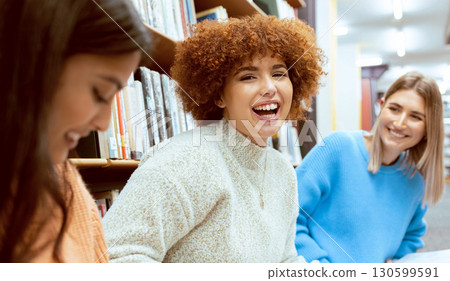 Friends, women and students in library, conversation or happiness while studying together, floor or focus. Female academics, girls or ladies with higher education, learning or ready for exams or test 130599591