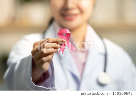 Breast Cancer Awareness. Doctor holding pink ribbon with a smile. Breast Cancer Awareness. Doctor holding pink ribbon with a smile. 130599642