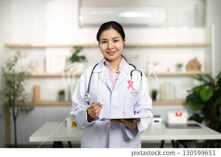 Breast Cancer Awareness. Confident female doctor holding clipboard and smiling. Breast Cancer Awareness. Confident female doctor holding clipboard and smiling. 130599651