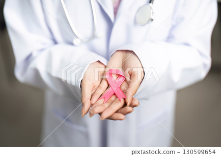 Breast Cancer Awareness. Doctor holding pink ribbon in hands, symbolizing hope. Breast Cancer Awareness. Doctor holding pink ribbon in hands, symbolizing hope. 130599654