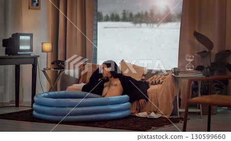 Bored, man and in home sitting in pool in the lounge in a retro home watching vintage TV with no signal. Winter, snow and hipster relaxing in the living room in a house during vacation or a holiday Bored, man and in home sitting in pool in the lounge in a retro home watching vintage TV with no signal. Winter, snow and hipster relaxing in the living room in a house during vacation or a holiday 130599660