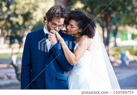 Wedding, couple and kiss while holding hands outdoor at marriage celebration event together with commitment. Interracial man and woman with trust, partnership and respect or care in nature park Wedding, couple and kiss while holding hands outdoor at marriage celebration event together with commitment. Interracial man and woman with trust, partnership and respect or care in nature park 130599753