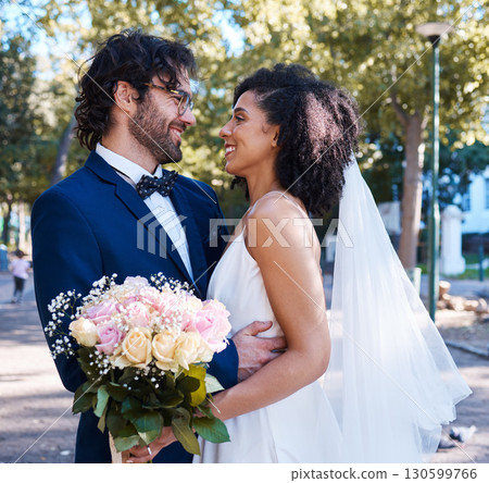 Interracial wedding and couple with flowers and hug at romantic outdoor marriage event celebration together. Partnership, commitment and trust embrace of happy bride and groom with smile. 130599766