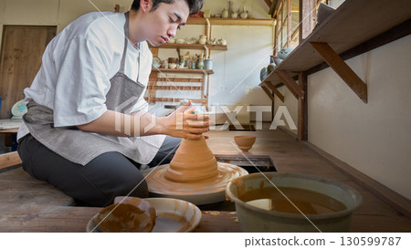 A man shaping a piece in a pottery studio A man shaping a piece in a pottery studio 130599787