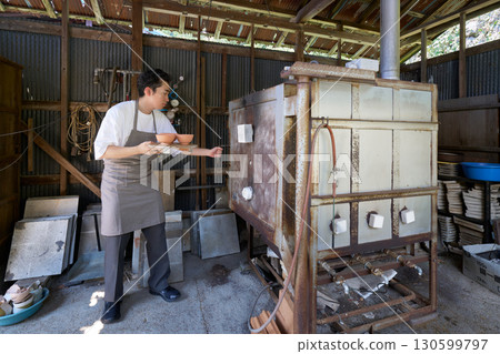 A young craftsman putting pottery into a pottery kiln 130599797