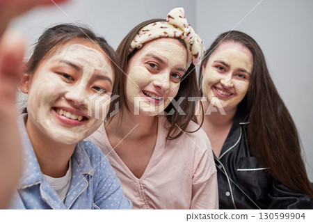 Friends, women and sleepover with mask, selfie and bonding with cosmetics, smile and quality time. Females, girls and photo for posting, dermatology or skincare with ladies, treatment or fun together 130599904