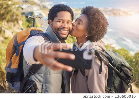 Selfie, kiss and black couple hiking on mountain for fitness, fun and romantic walk in natural landscape. Romance, man and woman taking self portrait in nature with smile in mountains on island trip 130600010