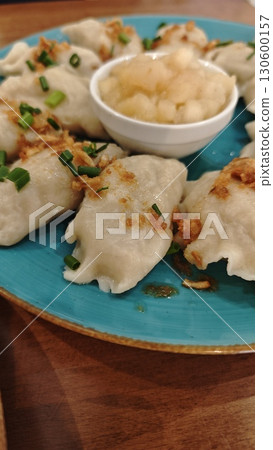 Traditional dumplings served with fried onions and green herbs on a turquoise plate with sauce Traditional dumplings served with fried onions and green herbs on a turquoise plate with sauce 130600157