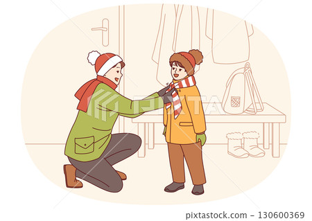 Caring father helps kid put on winter clothes so as not to freeze while walking along cold street 130600369