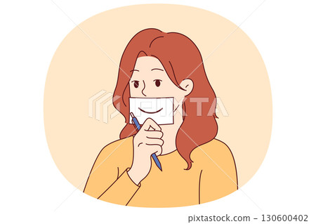 Woman shows fake smile, symbolizing happiness, by placing piece of paper with drawn mouth on face 130600402