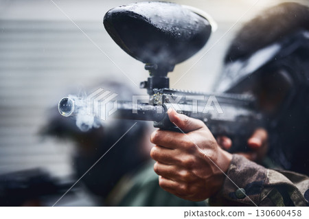Hand, paintball and gun with a sports man playing a military game for training or fun outdoor. Fitness, exercise and safety with a male player using a marker to shoot during a competitive tournament 130600458