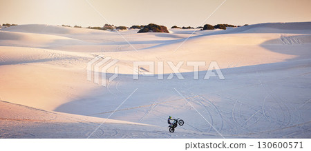 Desert, motorcycle and athlete doing a sport jump for outdoor competition, training or exercise. Extreme sports, sand dunes and man riding motorbike doing skill, trick or challenge for race in Dubai. Desert, motorcycle and athlete doing a sport jump for outdoor competition, training or exercise. Extreme sports, sand dunes and man riding motorbike doing skill, trick or challenge for race in Dubai. 130600571