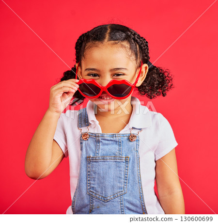 Child portrait, fashion and glasses on isolated red background in summer trend, holiday style and cool vacation. Smile, happy and kid with sunglasses for eyes healthcare, wellness and sun protection 130600699