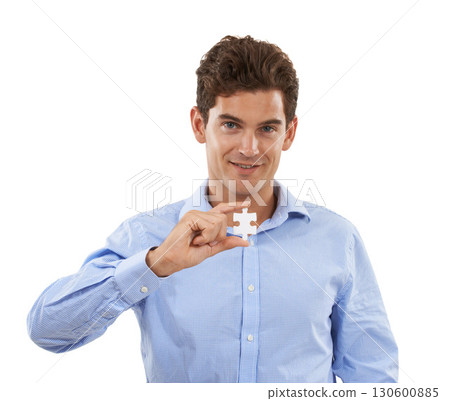 Portrait, puzzle and problem solving with a man in studio isolated on a white background holding a piece. Face, creative or connect and a male employee looking confident with a jigsaw in hand 130600885