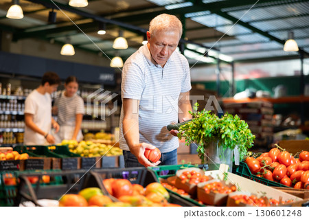 Elderly man choosing fresh tomatoes and cucumbers in grocery store Elderly man choosing fresh tomatoes and cucumbers in grocery store 130601248