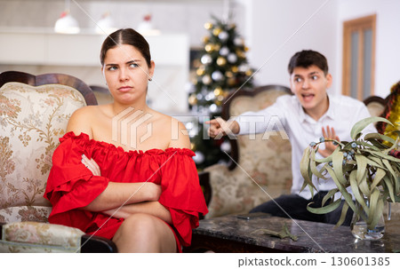 Disappointed young couple arguing among themselves before Christmas Eve while sitting on sofa in living room at home Disappointed young couple arguing among themselves before Christmas Eve while sitting on sofa in living room at home 130601385