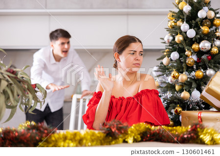 Annoyed young male and female getting mad at each other while standing near of Christmas tree in apartment Annoyed young male and female getting mad at each other while standing near of Christmas tree in apartment 130601461