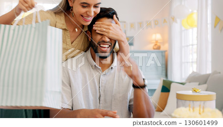 Birthday, surprise and couple with gift, cake and celebration, love and having fun while bonding at home. Event, present and playful woman with man in a living room with guess, game or package bag 130601499