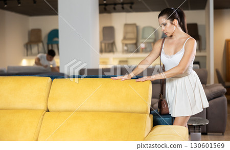 Adult woman chooses sofa in store 130601569