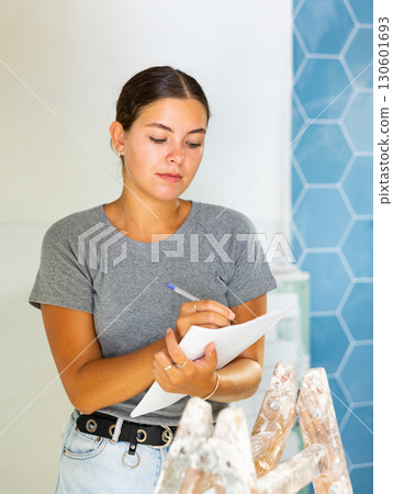 Young woman makes notes on paper while standing in the bathroom Young woman makes notes on paper while standing in the bathroom 130601693
