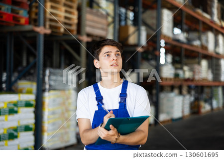 Young guy warehouse worker checking documents Young guy warehouse worker checking documents 130601695
