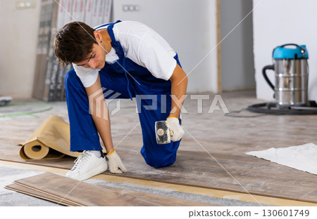 Male repairer installing laminate flooring in apartment Male repairer installing laminate flooring in apartment 130601749