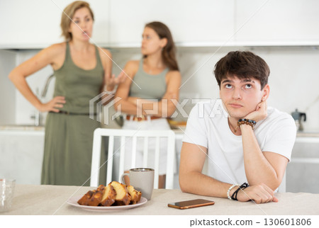 Bored guy is sitting at kitchen and unwittingly listens to mothers altercation with adult daughter Bored guy is sitting at kitchen and unwittingly listens to mothers altercation with adult daughter 130601806