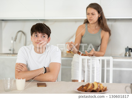 Young woman quarrels with young guy in kitchen Young woman quarrels with young guy in kitchen 130601817