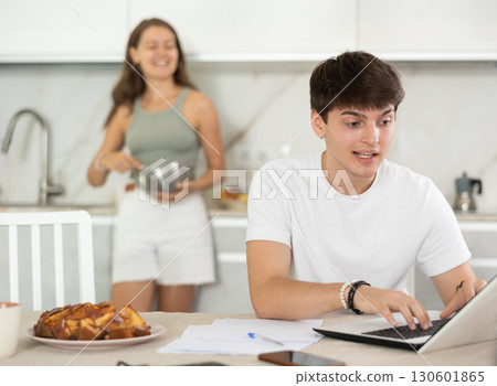 Young woman smiling and chatting with guy working at laptop 130601865