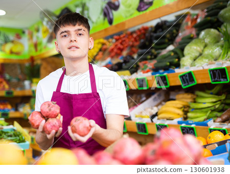 Hardworking young salesman puts pomegranates on the counter 130601938