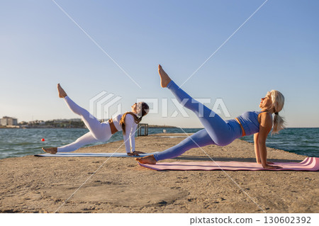 Yoga Women Beach Fitness - Two women practicing yoga on a beach. 130602392