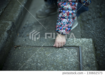 Child's hand putting a stone into the groove 130602573