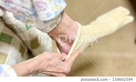 Elderly woman in the middle of putting on yellow socks 130602594