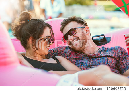 Happy, relax and couple talking at a party, conversation and holiday together in summer. Drinks, smile and man and woman in communication at a pool social to celebrate, have fun and vacation in Bali Happy, relax and couple talking at a party, conversation and holiday together in summer. Drinks, smile and man and woman in communication at a pool social to celebrate, have fun and vacation in Bali 130602723