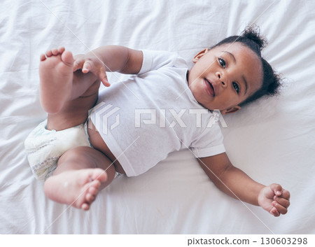 Happy baby, portrait and girl on a bedroom bed relax and calm in a nursery after rest. Young newborn, child and kid with a diaper in the morning with wellbeing and childcare from above in a house 130603298