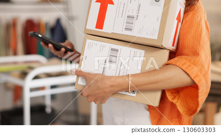 Hands, woman and boxes for logistics, phone and clothes for e commerce in warehouse, workshop and startup. Small business, smartphone and designer with contact, supply chain, store and shipping app Hands, woman and boxes for logistics, phone and clothes for e commerce in warehouse, workshop and startup. Small business, smartphone and designer with contact, supply chain, store and shipping app 130603303