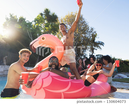 Pool party, beer and friends on flamingo, having fun and partying. Summer celebration, water event and group portrait of drunk funny people laughing with alcohol, swimming and floating on bird float. Pool party, beer and friends on flamingo, having fun and partying. Summer celebration, water event and group portrait of drunk funny people laughing with alcohol, swimming and floating on bird float. 130604073