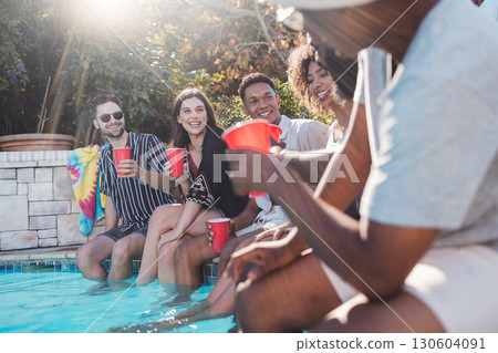 Vacation, drinks and friends speaking in a pool at a summer party, celebration or event at a home. Diversity, happy and people talking, having fun and bonding by the swimming pool while drinking. 130604091