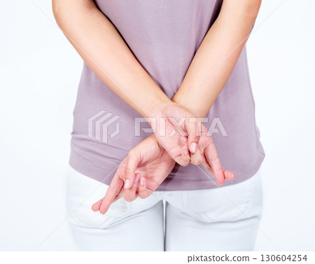 Back, closeup and fingers crossed for hope, woman and waiting for blessing with girl isolated on white studio background. Zoom, young female and gesture for believe, hands and liar with good luck 130604254
