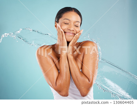 Water, splash and woman in a studio for a skincare, beauty and natural cosmetic face routine. Health, wellness and female model with a fresh organic facial treatment isolated by a blue background. 130604405