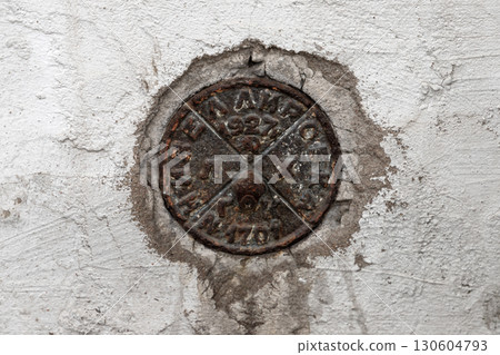 An element of a leveling benchmark in the wall of an old house in Saint-Petersburg 130604793