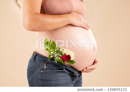 Pregnant woman, rose flowers and stomach in studio for body, maternity wellness and ivf healthcare. Closeup abdomen, floral plants and pregnancy of mother for baby belly, gynecology and natural birth 130605233
