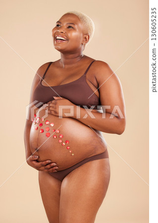Pregnant, black woman and smile with flowers on belly in studio for body, baby wellness and ivf healthcare. Mother, pregnancy and floral plants on stomach with happiness, beauty or natural childbirth Pregnant, black woman and smile with flowers on belly in studio for body, baby wellness and ivf healthcare. Mother, pregnancy and floral plants on stomach with happiness, beauty or natural childbirth 130605235