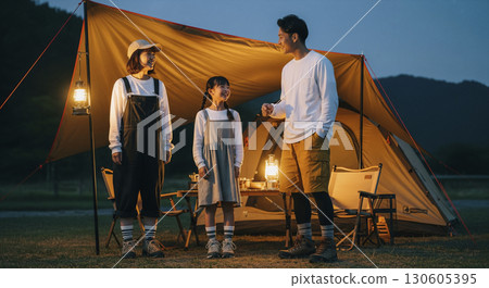 Family enjoying the sunset with lanterns lit - camping scene 130605395