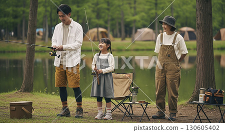 父子倆在湖邊釣魚，母親在一旁注視著他們。露營場景。 130605402