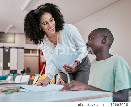 Paper, education or happy teacher with a child in a class to help learning development or studying. Writing, notebook or fun black woman smiles teaching, talking or speaking to an African school boy Paper, education or happy teacher with a child in a class to help learning development or studying. Writing, notebook or fun black woman smiles teaching, talking or speaking to an African school boy 130605638