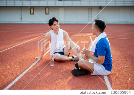 Two asian athlete men are taking a rest, sitting together on the racetrack. Jogging or Running. Two asian athlete men are taking a rest, sitting together on the racetrack. Jogging or Running. 130605904