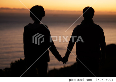 Sunset, beach and silhouette of couple holding hands for date by the sea with dark shadow, love and care. Horizon, ocean and people rear with together in nature for hiking or travel goals on holiday Sunset, beach and silhouette of couple holding hands for date by the sea with dark shadow, love and care. Horizon, ocean and people rear with together in nature for hiking or travel goals on holiday 130605994