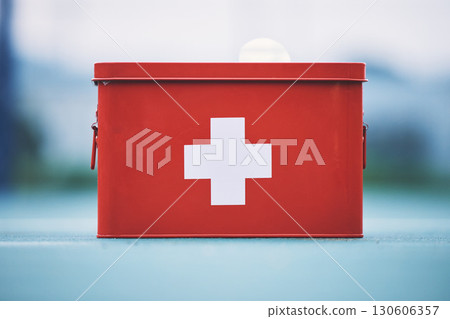 First aid, box and medical equipment for health emergency, response and treatment kit isolated in a blurred background. Red, cross and safety or medicine on a table for fast healthcare or cure 130606357