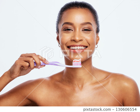 Portrait, dental and a black woman brushing teeth in studio isolated on a white background for oral hygiene. Face, toothbrush and toothpaste with an attractive young female posing on blank space 130606554